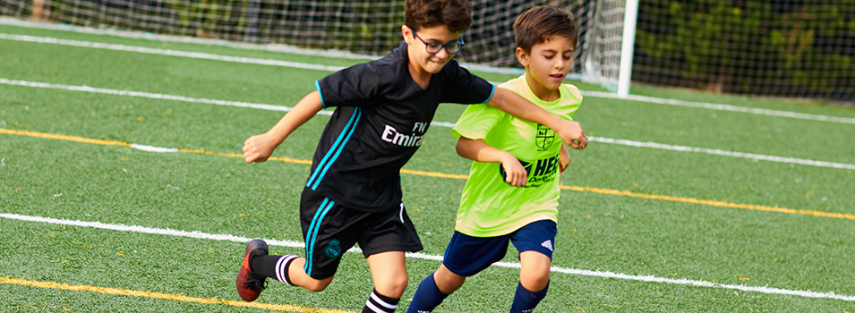 Boy with eyeglasses plays soccer with another boy